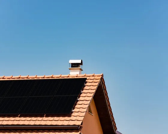 Paneles solares fotovoltaicos en tejado de tejas naranjas con cielo azul claro